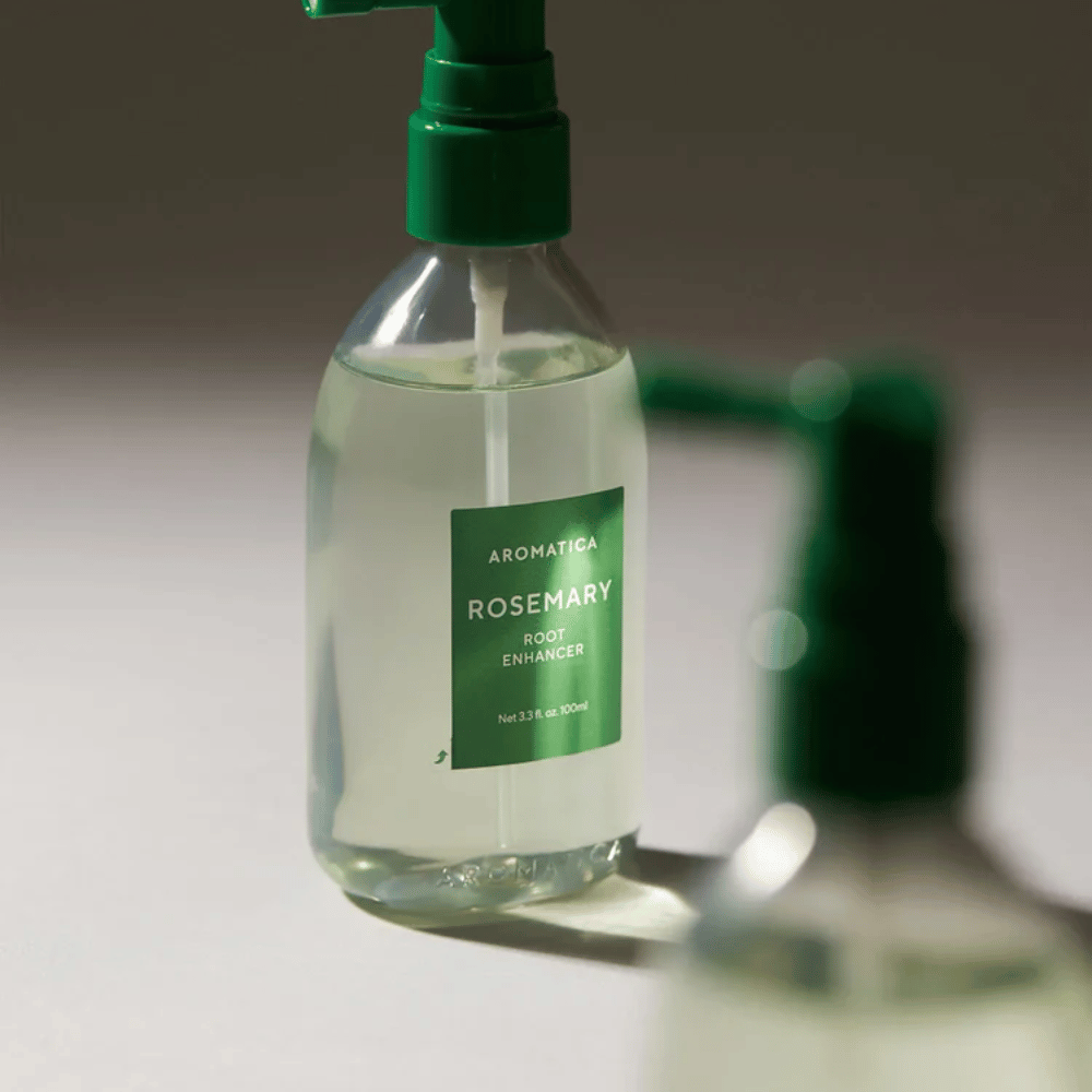 Detailný záber na AROMATICA Rosemary Root Enhancer so zeleným aplikačným nadstavcom. Obrázok sa zameriava na dizajn fľaše a presnú aplikáciu priamo na pokožku hlavy.