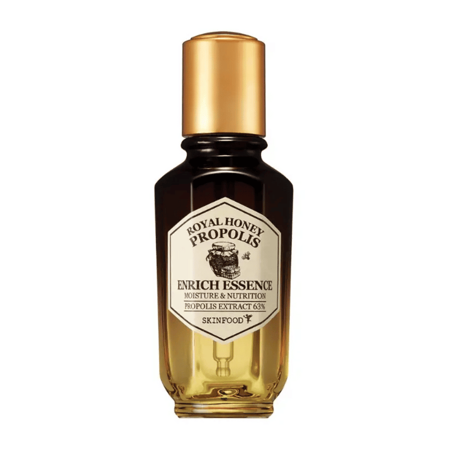 Obrázok sklenenej fľaše s tmavou tekutinou a zlatým uzáverom. Na etikete fľaše je napísané "Royal Honey Propolis Enrich Essence" nasledované "Moisture & Nutrition" a "Propolis Extract 63%". Značka "Skinfood" je tiež viditeľná na spodku etikety.
