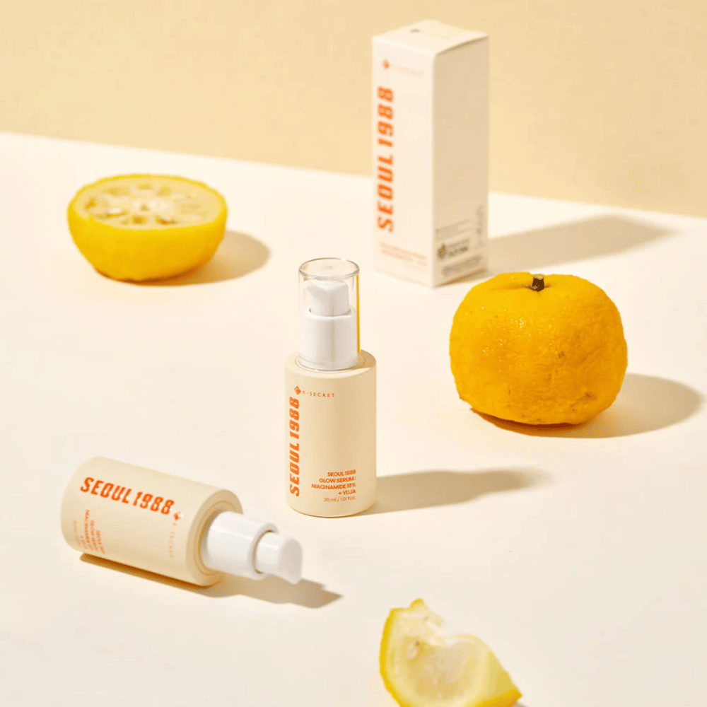 Viac fliaš a balení Seoul 1988 Glow Serum usporiadaných s celými a polovičnými yuja plodmi v pozadí.