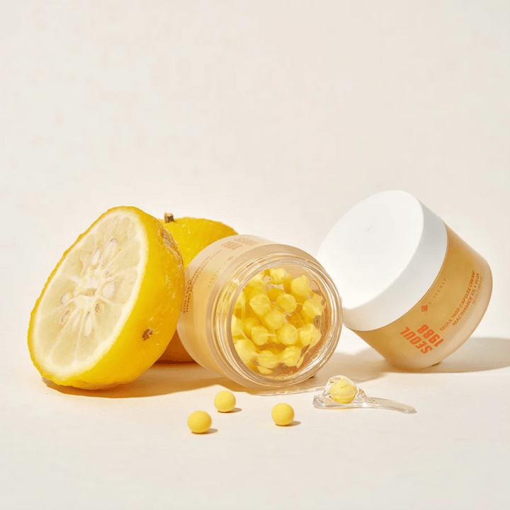 Otvorená nádoba so žltými kapsulami vedľa polovičného ovocia yuja, ktoré zvýrazňuje formulu bohatú na vitamín C.