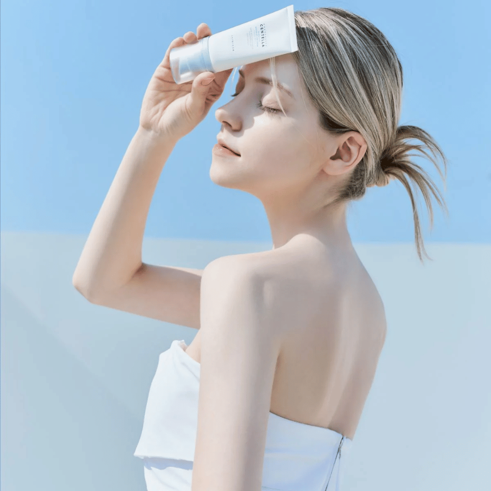 Žena aplikuje SKIN1004 Madagascar Centella Hyalu-Cica Water-Fit Sun Serum 50ml na ochranu tváre pred UV lúčmi.