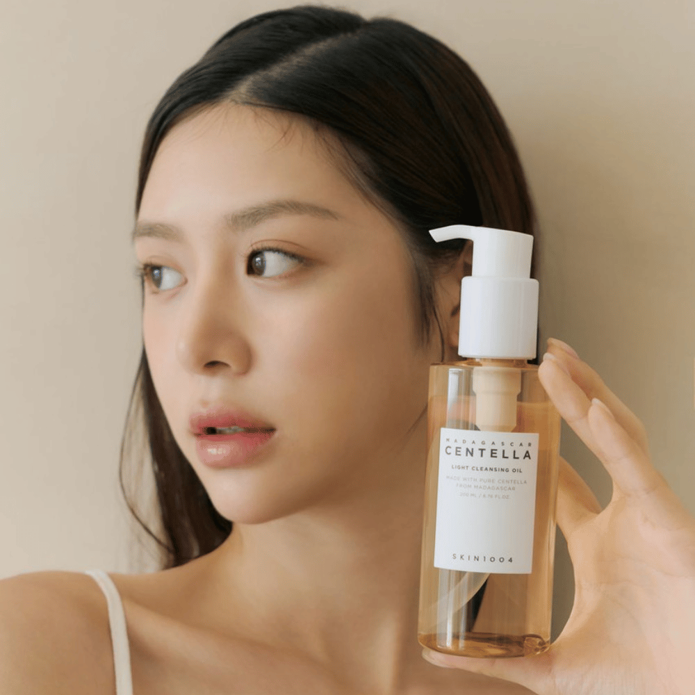 Žena, ktorá drží fľašu SKIN1004 Madagascar Centella Light Cleansing Oil 200 ml čistiaceho prostriedku na tvár.