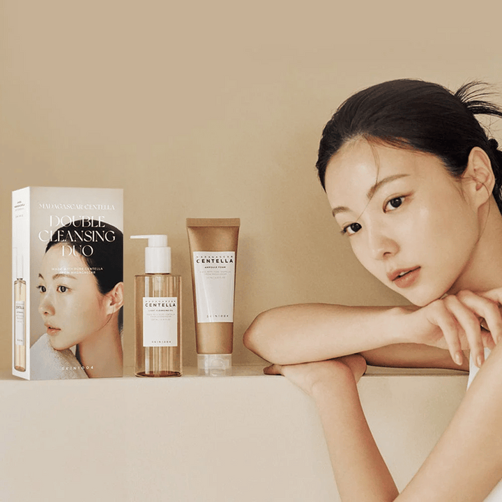 SKIN1004 Madagascar Centella Double Cleansing Duo Set s kartónom, olejovým čistením, penovým čistením a modelkou s hydratovanou pokožkou proti béžovému pozadiu.