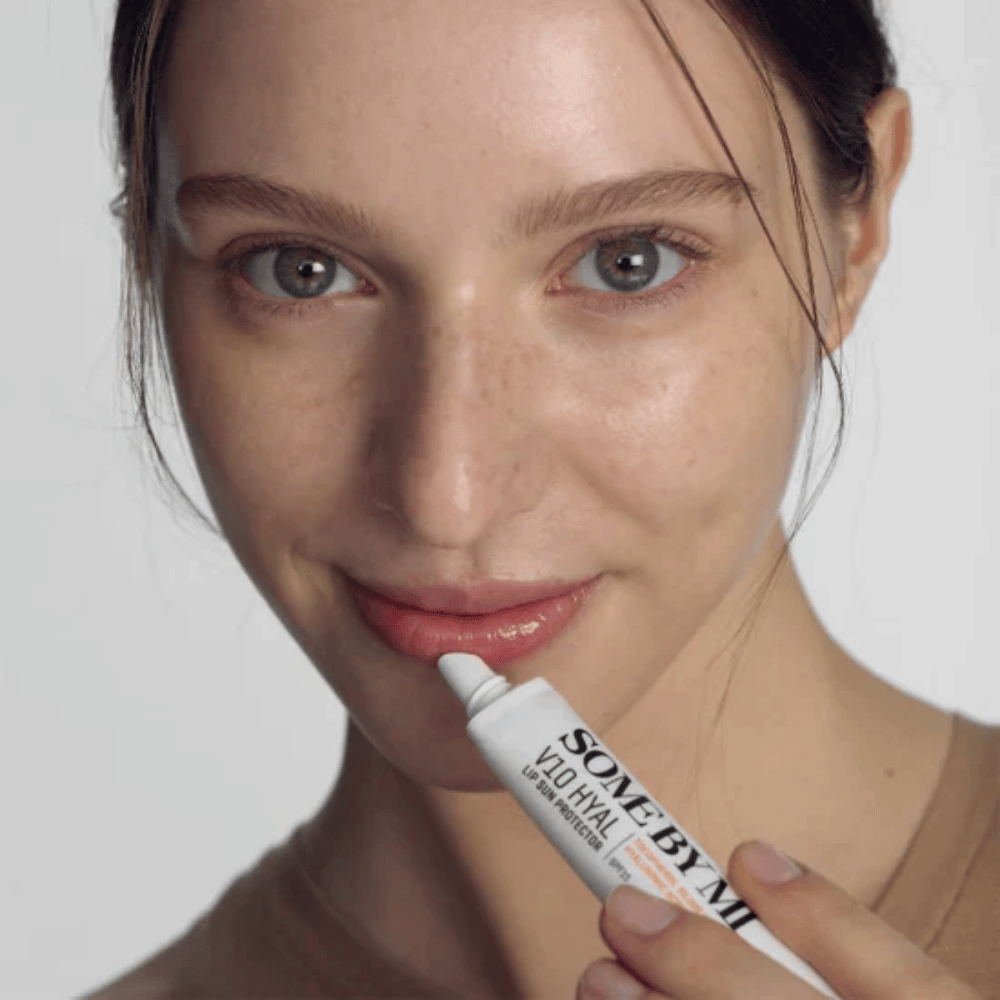 Žena drží tubu V10 Hyal Lip Sun Protector SPF15 7ml balzamu na pery na ochranu pred slnkom a hydratáciu, od SOME BY MI.