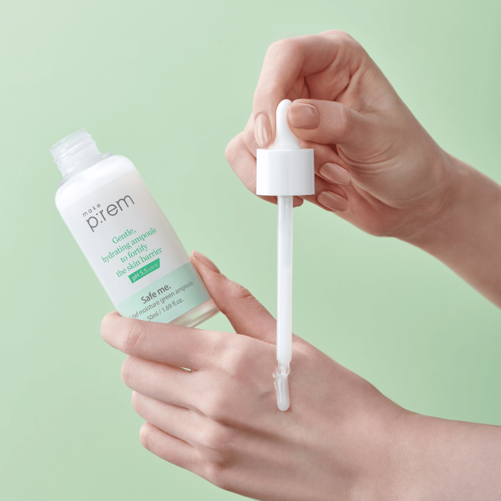 Ruky držia otvorenú fľašu a pipetu Safe Me Relief Moisture Green Ampoule proti jemne zelenému pozadiu.