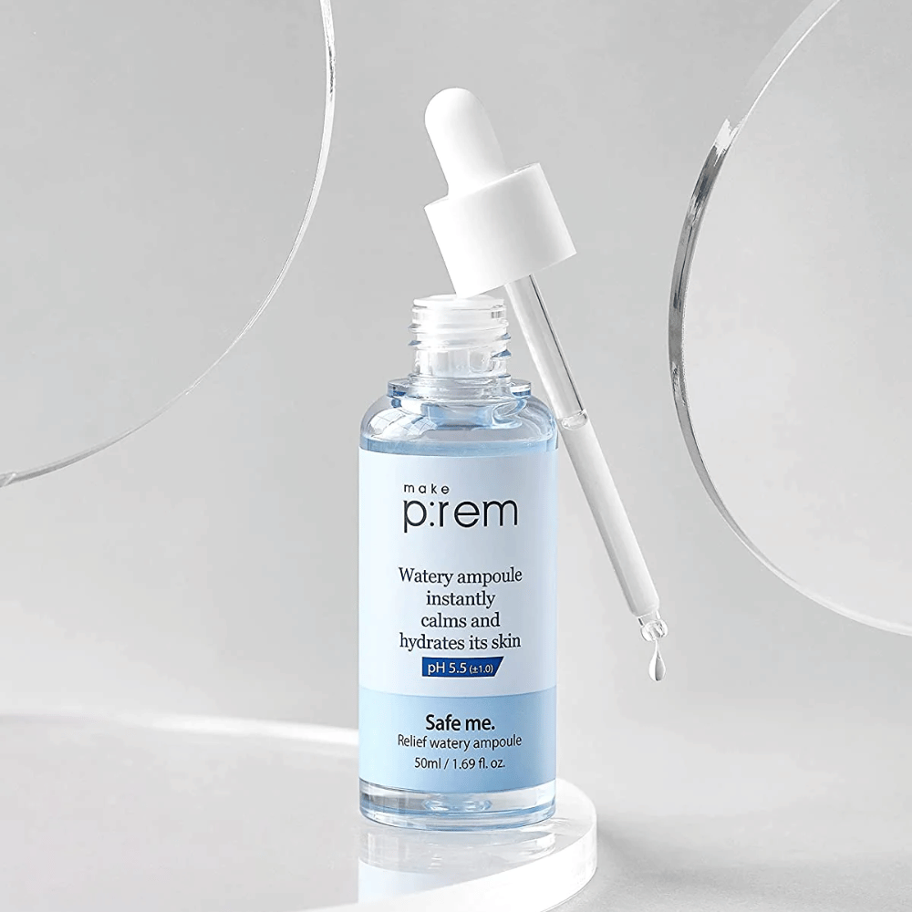 Priehľadná modrá fľaša Safe Me Relief Watery Ampoule s pipetou, kvapky vody, na sivom pozadí a zrkadle.