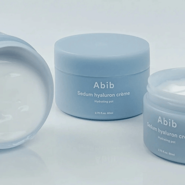 Tri nádoby Abib Sedum Hyaluron Crème Hydrating Pot 80 ml v svetlomodrom minimalistickom dizajne, z ktorých jedna otvorená nádoba ukazuje krémovú bielu konzistenciu.