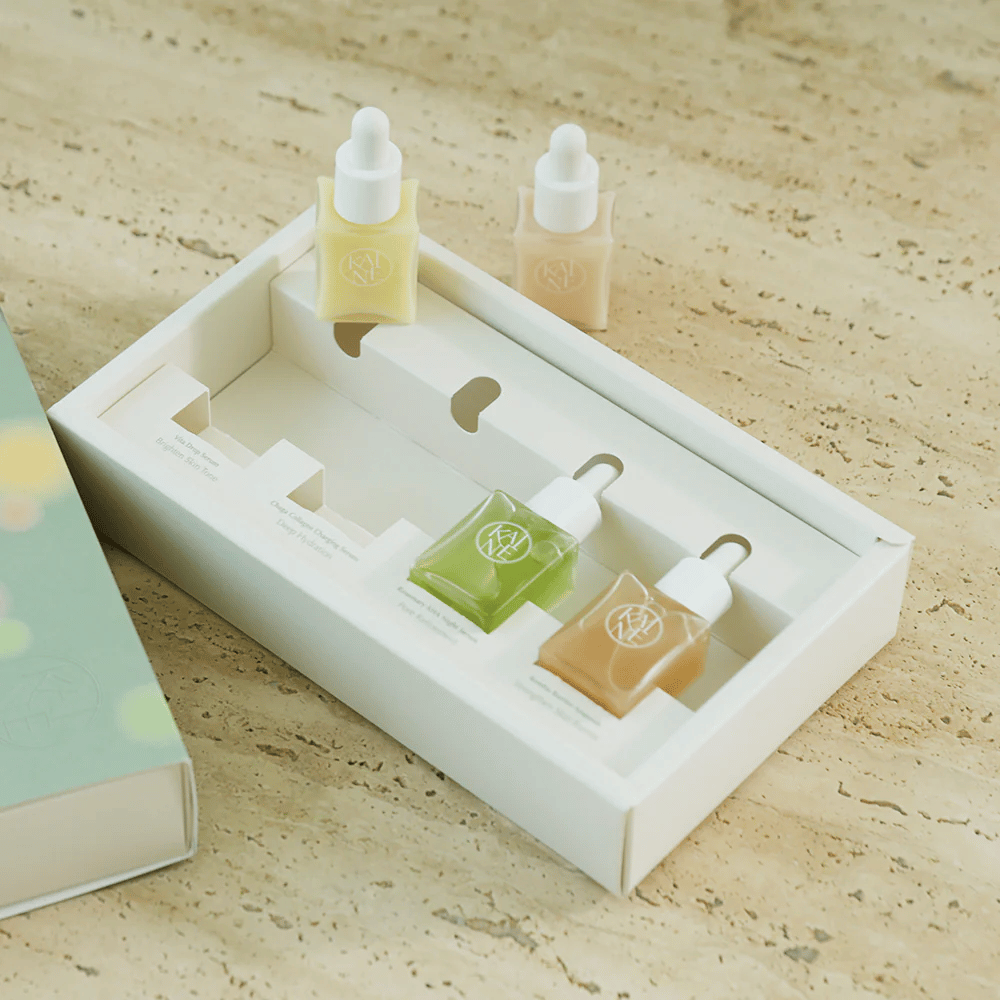 Štyri farebné fľaštičky séra z KAINE Serum Discovery Kit s pipetovým uzáverom, navrhnuté tak, aby vyhovovali rôznym potrebám pleti v minimalistickom a elegantnom balení.