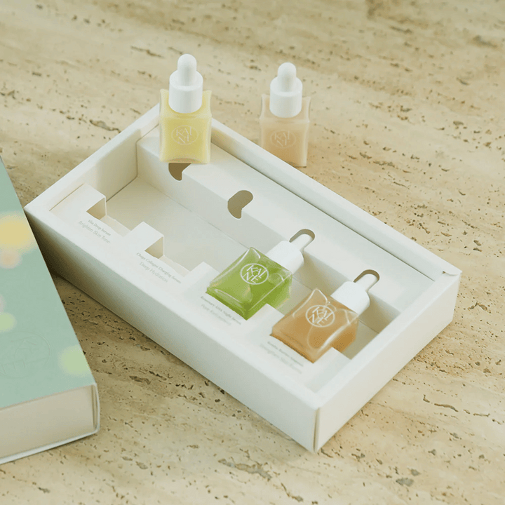 Štyri farebné fľaštičky séra z KAINE Serum Discovery Kit s pipetovým uzáverom, navrhnuté tak, aby vyhovovali rôznym potrebám pleti v minimalistickom a elegantnom balení.