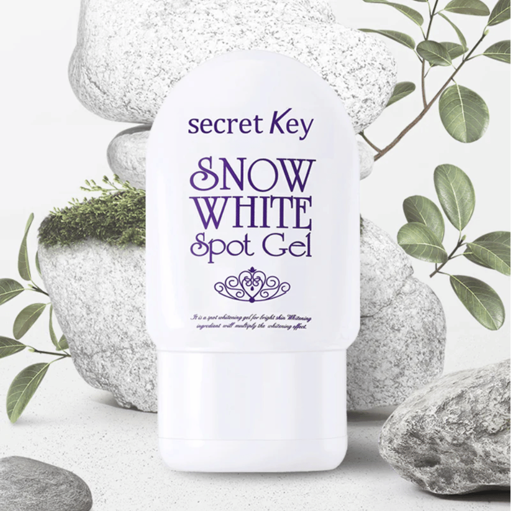 Secret Key Snow White Spot Gel fotografovaný proti kameňom a zeleným listom.