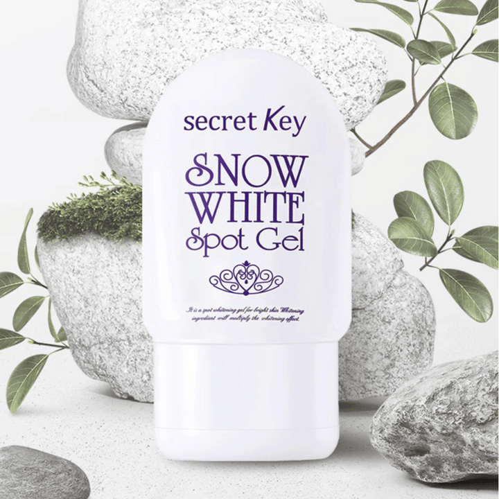 Secret Key Snow White Spot Gel fotografovaný proti kameňom a zeleným listom.