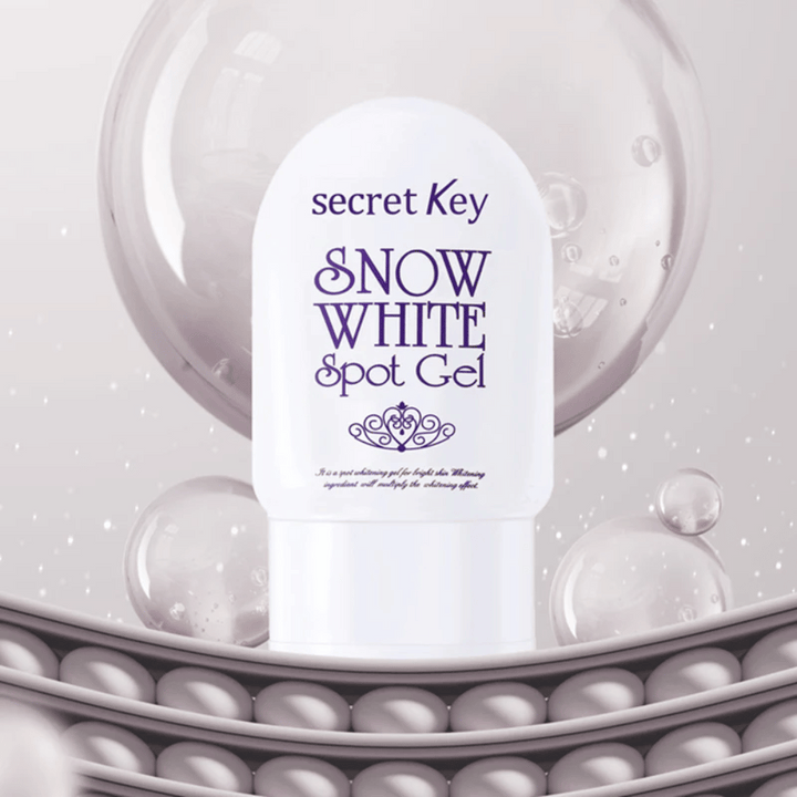 Secret Key Snow White Spot Gel v bielom obale na pozadí s bublinami a perlovými detailmi.