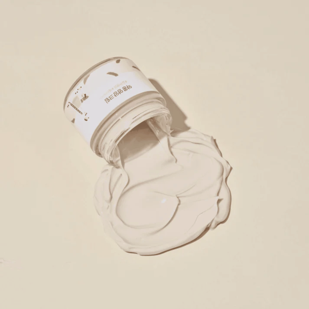 Mixsoon Soybean Nourishing Cream rozliaty z nádoby na béžovom pozadí. Krémová bohatá konzistencia ukazuje jeho intenzívne hydratačné vlastnosti.