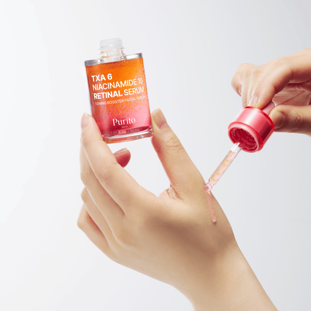 Ruka aplikuje Purito TXA 6 Niacinamide 10 Retinal Serum. Ľahká formula s aktívnymi zložkami pre žiarivosť, elasticitu a jasnejšiu pleť.