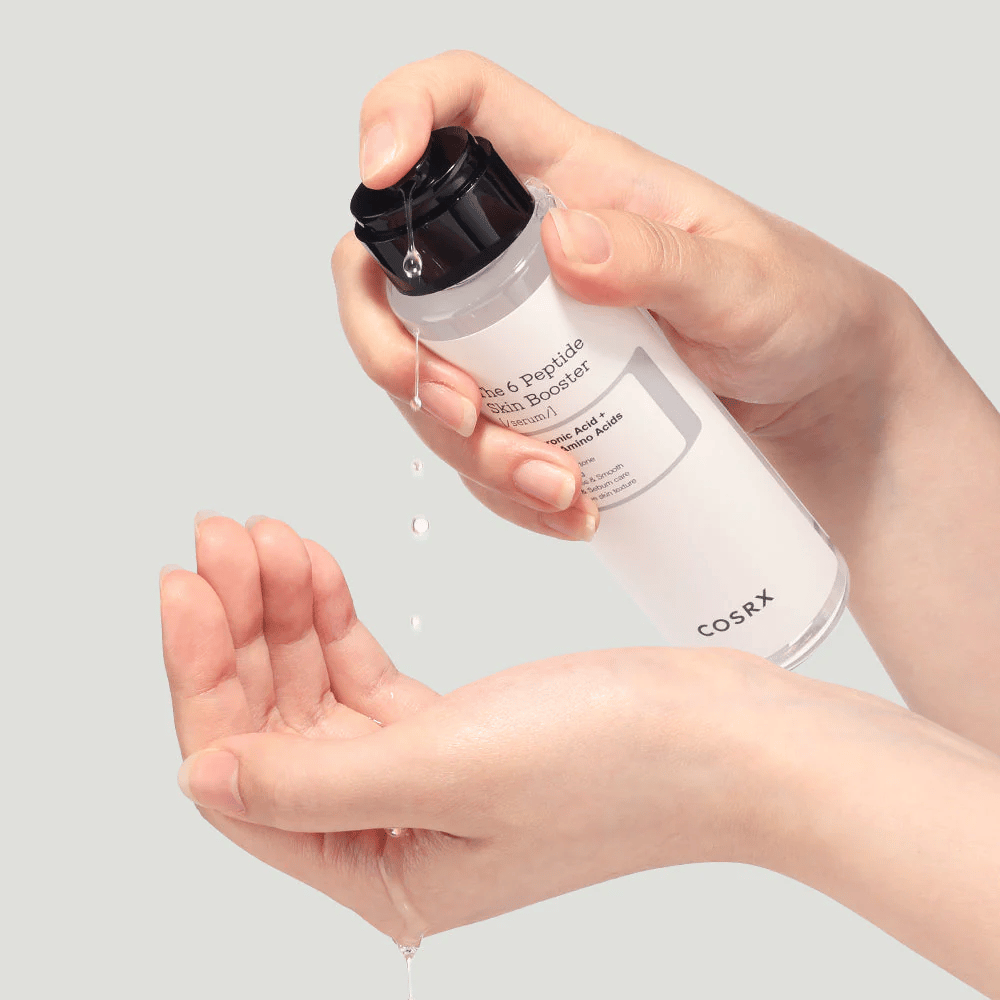 Ruky, ktoré vylievajú pleťový produkt z priehľadnej fľaše s nápisom "The Peptide Skin Booster".