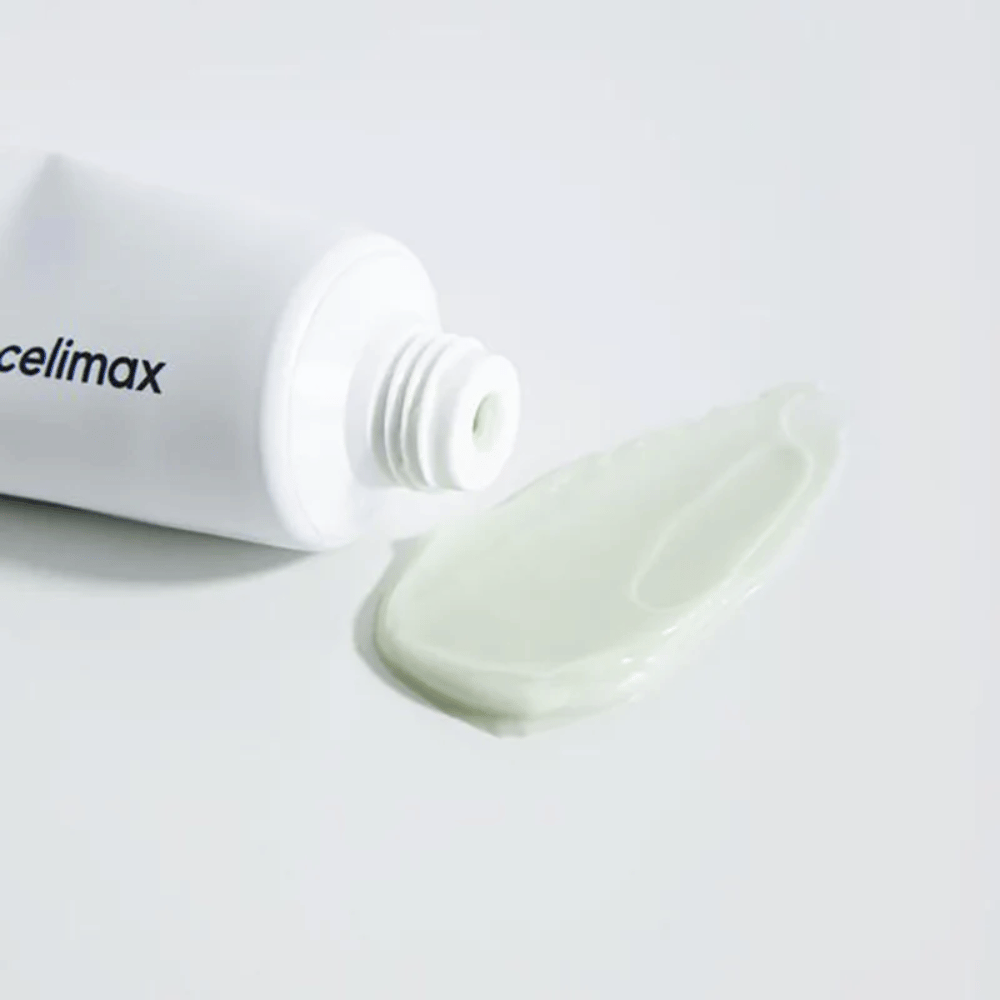Celimax Noni Energy Repair Cream v bielej tube s malým množstvom svetlozeleného krému vytlačeného vedľa tuby na bielom povrchu. Krém je určený na výživu a opravu pokožky.