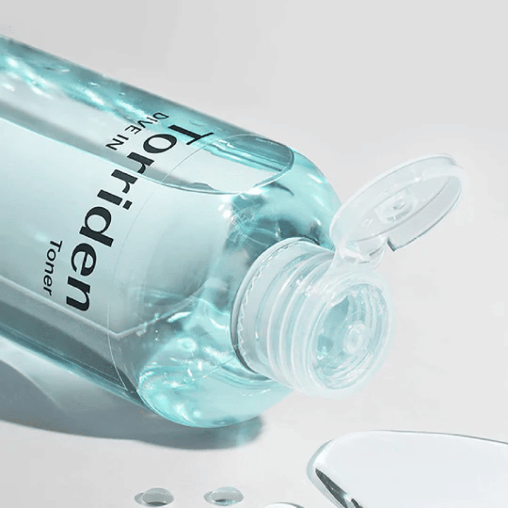 Fľaša DIVE-IN Low Molecule Hyaluronic Acid Toner 300ml vedľa pohára vody, podporuje Torriden a hydratáciu.