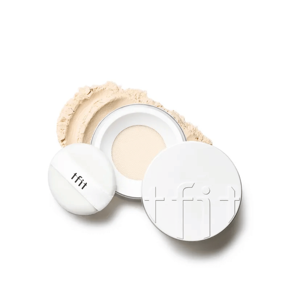 Otvorená dóza s TFIT Translucent Set Finishing Powder v odtieni Skin Beige, s priloženým púdrikom a práškom rozsypaným okolo.