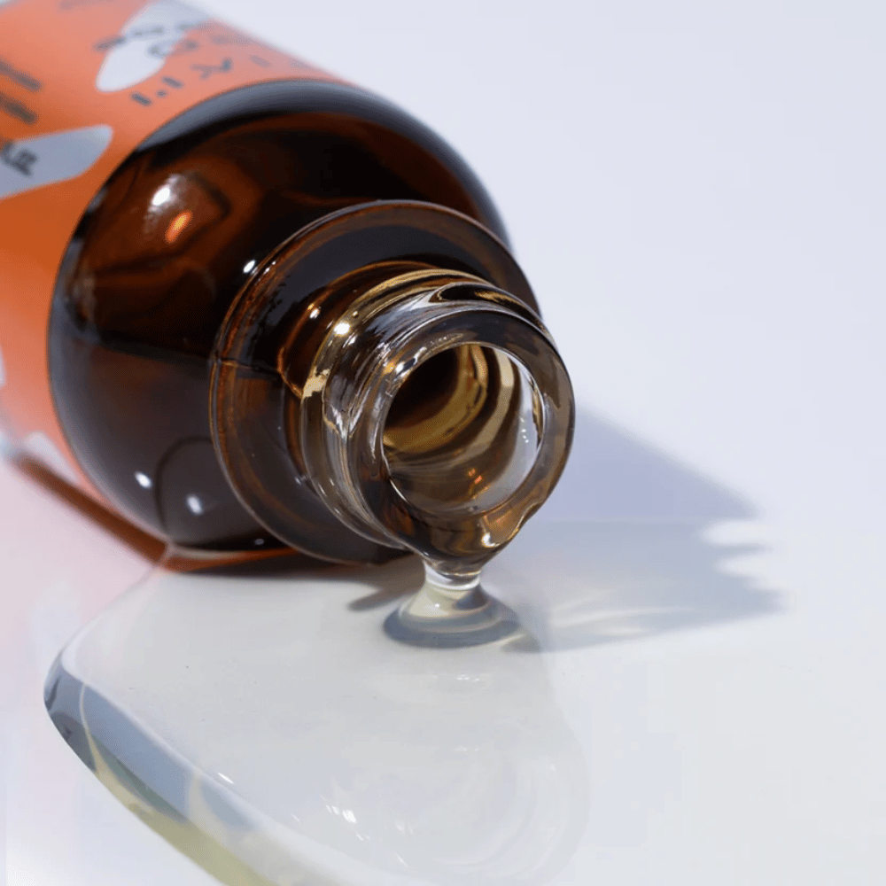 Detailný záber na sérum TIA'M Vita C Source, ktoré steká z hnedej sklenenej fľaše. Číra formula séra zvýrazňuje jeho koncentrovaný obsah vitamínu C pre žiarivú pokožku.