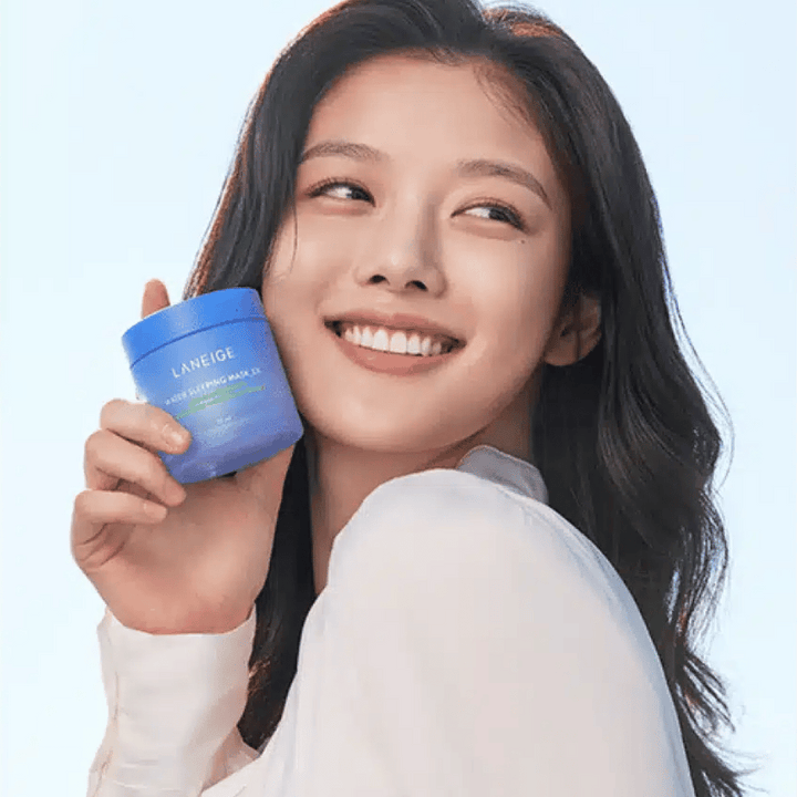 Usmievajúca sa žena drží modrú nádobu LANEIGE Water Sleeping Mask pred svetlomodrým pozadím.