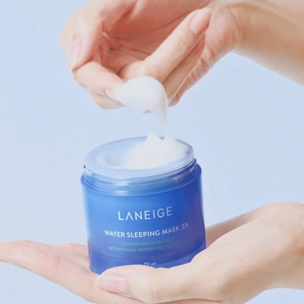 Ruka naberá LANEIGE Water Sleeping Mask z modrej nádoby, s dôrazom na gélovitú konzistenciu na svetlomodrom pozadí.