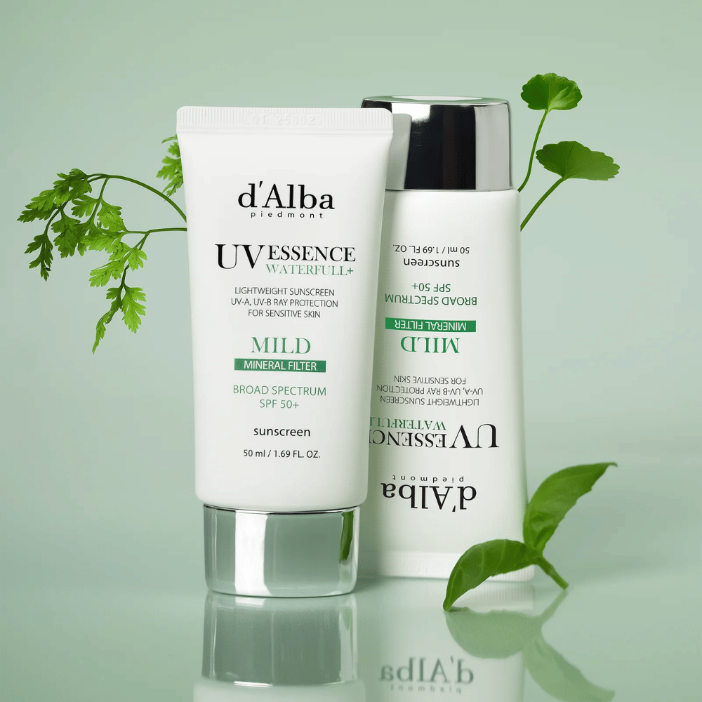 d'Alba Waterfull Mild Sun Cream SPF 50+ fotografovaný so zelenými listami. Jemný minerálny opaľovací krém so širokospektrálnou ochranou a hydratačnou formulou pre citlivú pokožku.