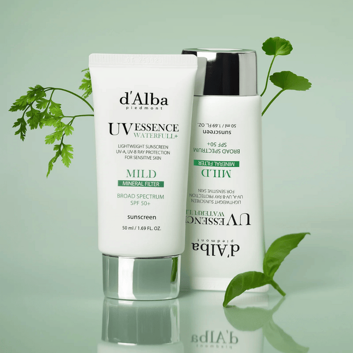d'Alba Waterfull Mild Sun Cream SPF 50+ fotografovaný so zelenými listami. Jemný minerálny opaľovací krém so širokospektrálnou ochranou a hydratačnou formulou pre citlivú pokožku.