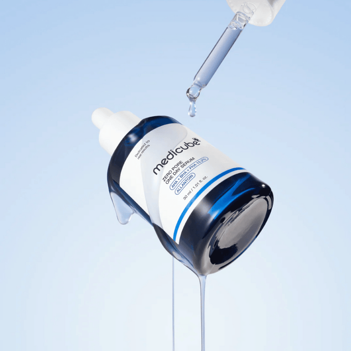 Fľaša Medicube Zero Pore One Day Serum s pipetou a kvapkajúcimi kvapkami séra na svetlomodrom pozadí.