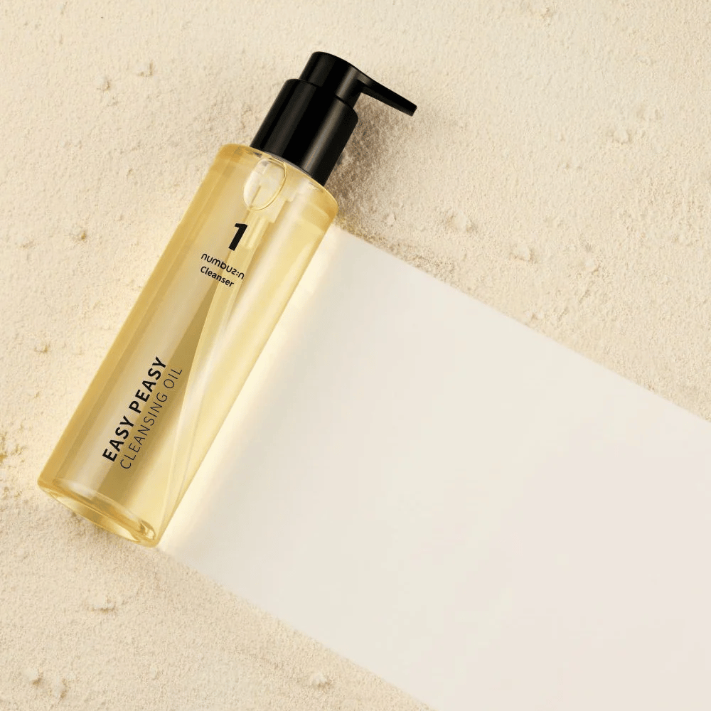 Numbuzin No.1 Easy Peasy Cleansing Oil ležiaca na pieskovo farebnom povrchu s tieňom.