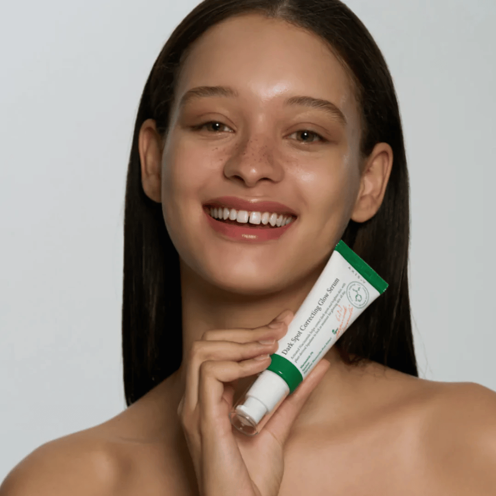 Mladá žena drží tubu AXIS - Y Dark Spot Correcting Glow Serum 50ml.