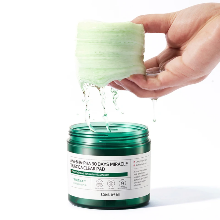 Ruka nalieva zelenú tekutinu do nádoby pre SOME BY MI:s AHA, BHA, PHA 30 Days Miracle Truecica Clear Pad 70 ks liečba akné.