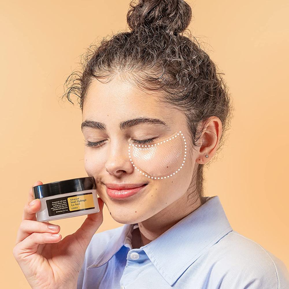 Žena, ktorá drží nádobu COSRX Advanced Snail Hydrogel Eye Patch 60 ks pleťového krému.