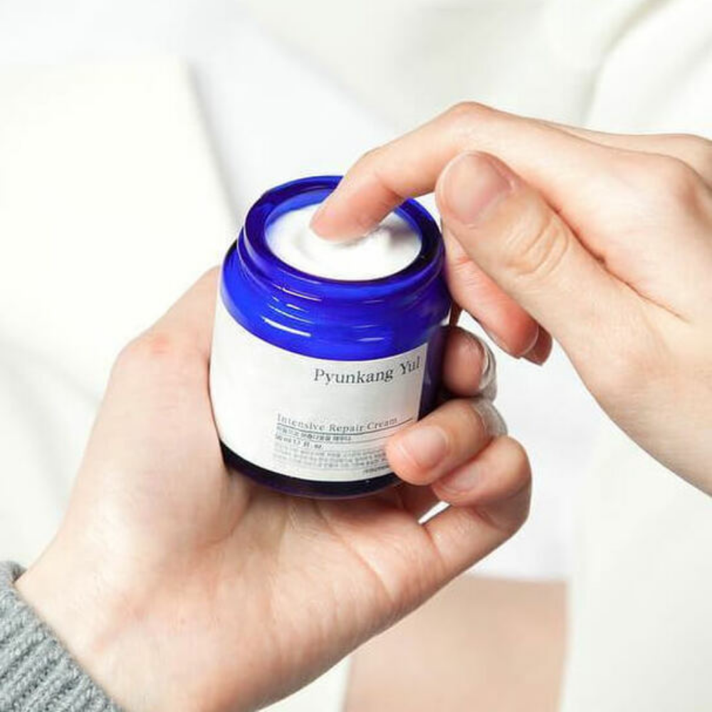 Osoba drží pohár Pyunkang Yul Intensive Repair Cream 50ml.