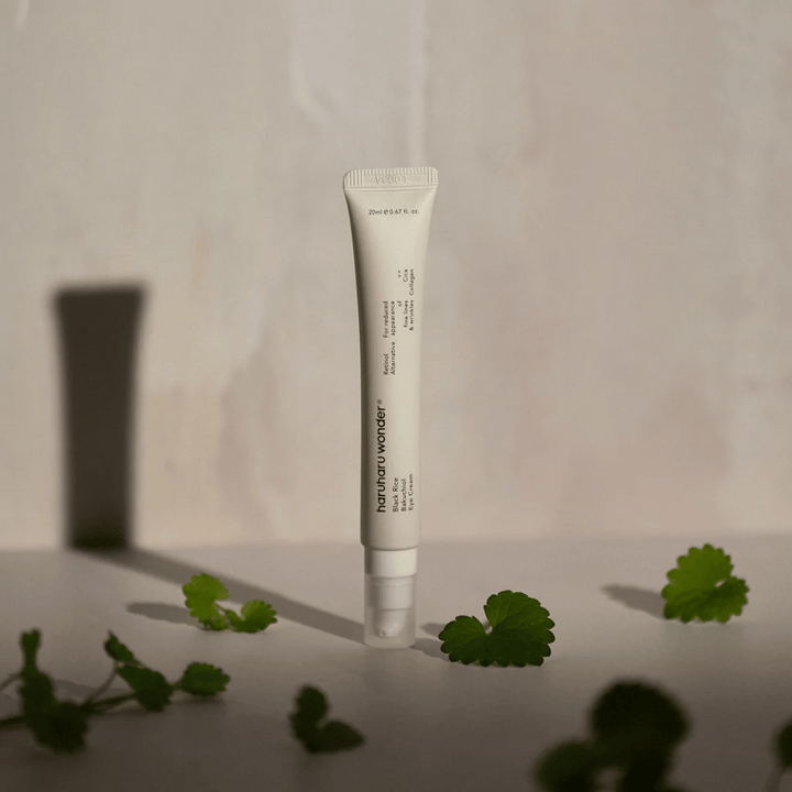 Tuba Haruharu Wonder Black Rice Bakuchiol Eye Cream 20ml obklopená zelenými listami, zameraná na viditeľnosť vrások a jemných liniek.