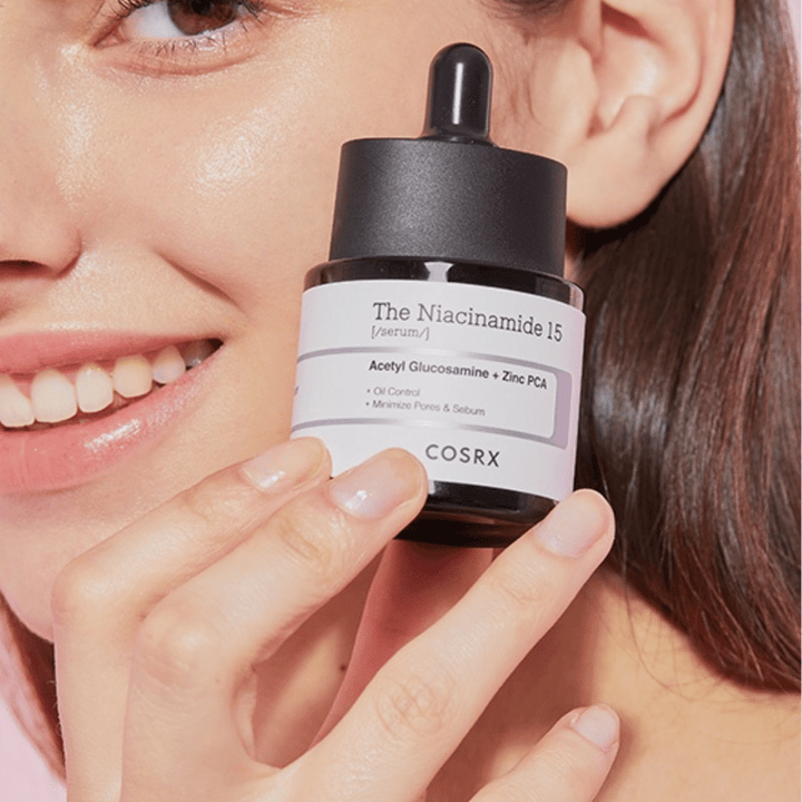 Žena drží fľašu COSRX Niacinamide 15 Serum 20ml pre niacínamid a produkciu mazu.