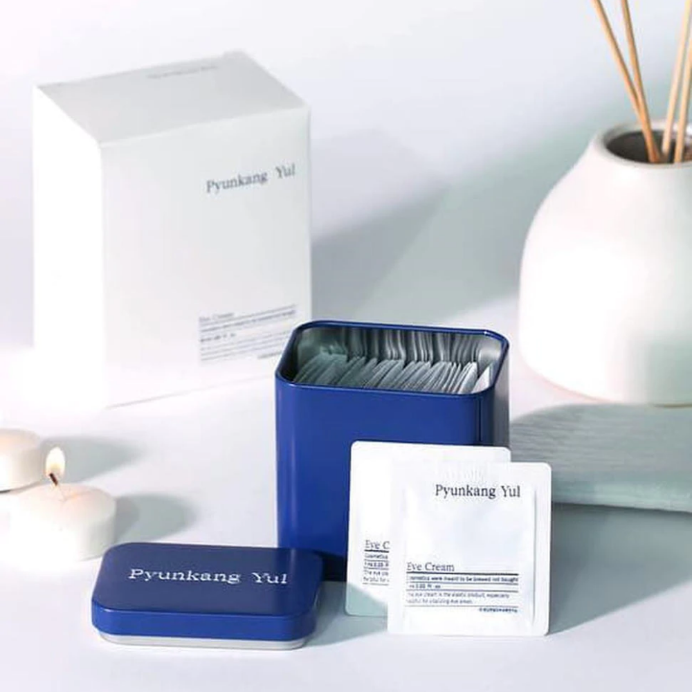 Biela škatuľka s modrým vekom a Pyunkang Yul Eye Cream 1ml x 50ks vedľa.