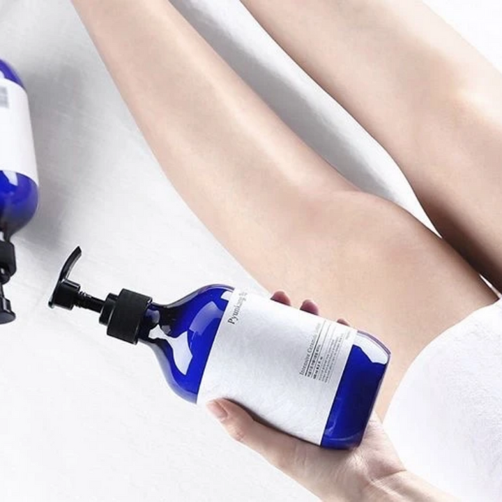 Žena, ktorá drží fľašu Pyunkang Yul Intensive Ceramide Lotion 500ml vedľa svojich nôh.