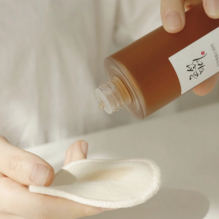 Osoba, ktorá nalieva Beauty of Joseon Ginseng Essence Water 150ml na handričku, aby riešila suchú pokožku a znížila produkciu mazu.