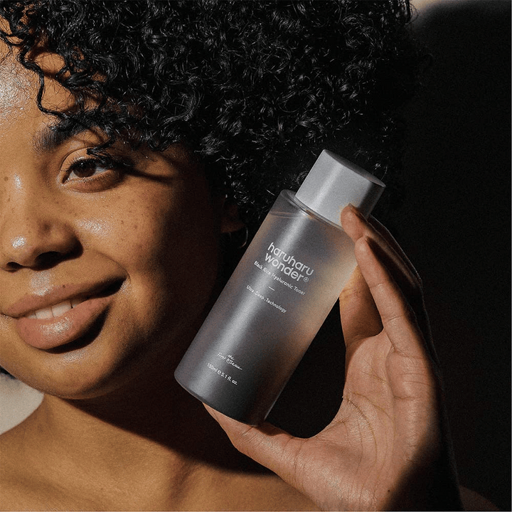Žena držiaca fľašu Haruharu Wonder Black Rice Hyaluronic Toner Original 150ml.
