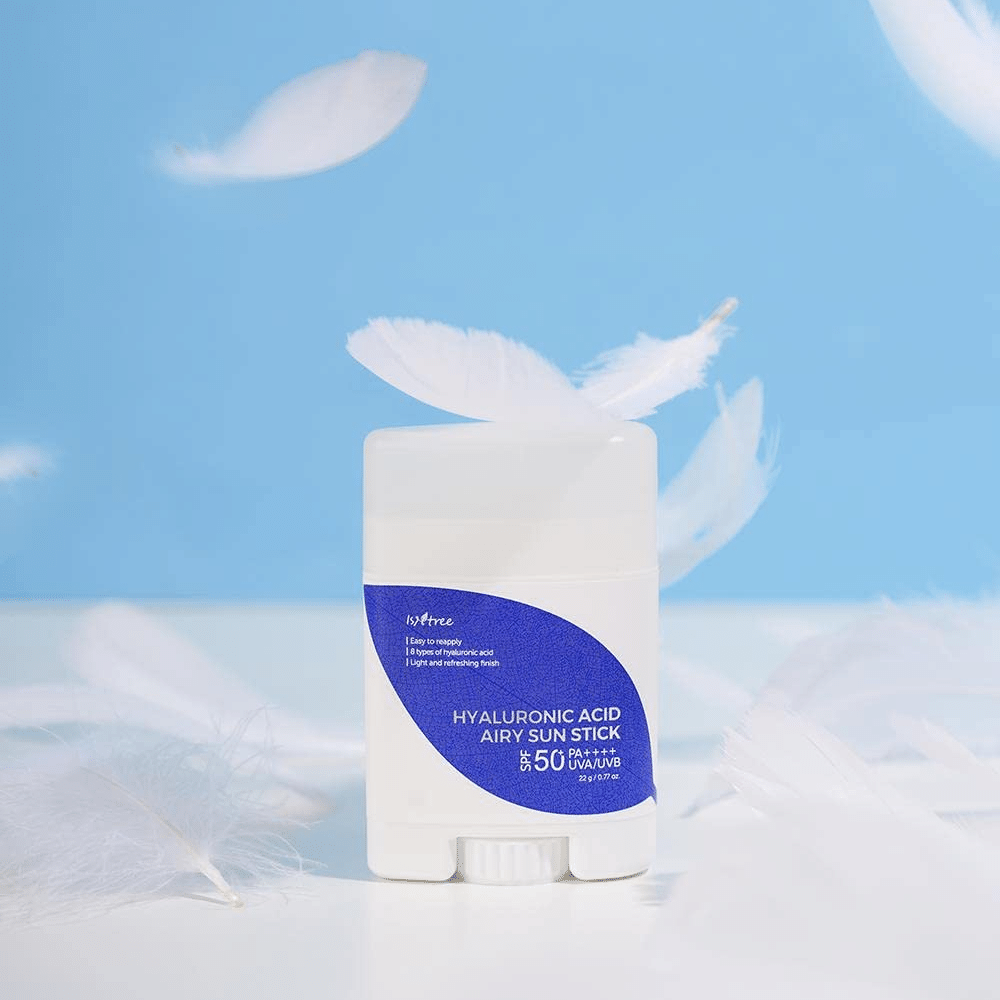 Isntree Hyaluronic Acid Airy Sun Stick s SPF 50+ a kyselinou hyalurónovou, ozdobená bielymi pierkami.