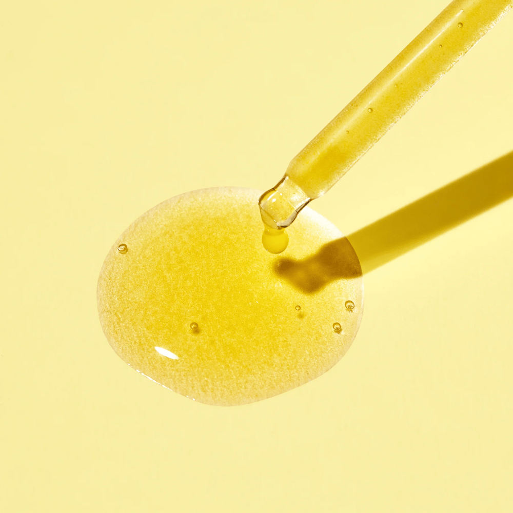 Kvapka tekutiny na žltom pozadí s MISSHAs Vita C Plus Spot Correcting & Firming Ampoule.