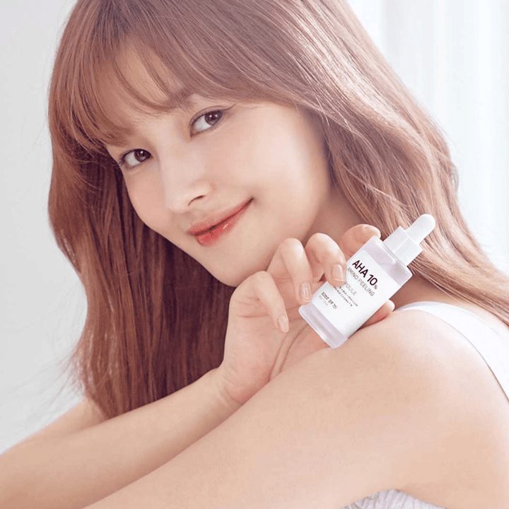 Mladá žena, ktorá drží fľašu SOME BY MI AHA 10% Amino Peeling Ampoule 35g, ktorá hydratuje pokožku.